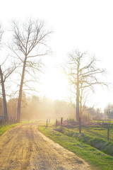 Obraz premium Sandy dirt road between agraric fields in a sunset flare during wintertime