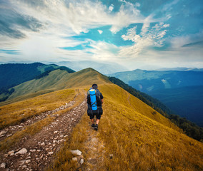 A tourist walks along a mountain meandering trail. Summer walking in mountains