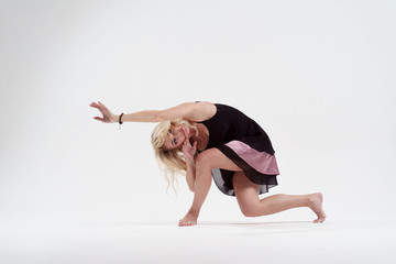 Photo of long-haired blonde looking to side with outstretched hand dancing in studio