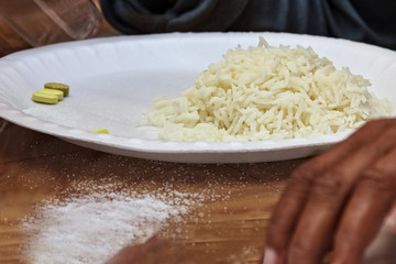 white cooked rice in a plate served with health supplements and salt discarded , a life style food for health conscious people.   