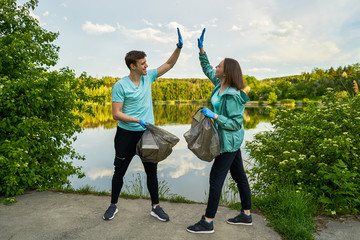 Plogging concept. Boy and girl picking up trash from the forest. They collecting the litter in...