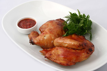 Half a baked chicken in sauce on a white plate