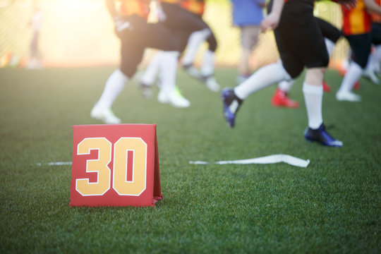 Picture of soccer field with number thirty running football players on blurred background
