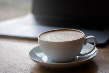A cup of coffee on desk, Cup of coffee in hand, mug of latte coffee, Close up concept.
