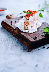 Frischkäse auf einem Holzbrett mit frischen Kräutern