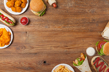 Mix of fast food, street dishes. Background with copy space. Top view. Natural wooden background.