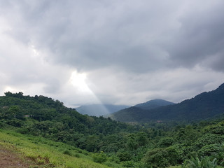 Fototapeta na wymiar Light beam passes through clouds shining over a tropical valley