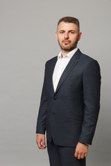 Handsome successful confident young business man in classic black suit shirt posing isolated on grey wall background, studio portrait. Achievement career wealth business concept. Mock up copy space.