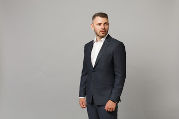 Handsome successful confident young business man in classic black suit shirt posing isolated on grey wall background, studio portrait. Achievement career wealth business concept. Mock up copy space.