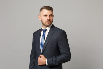 Handsome successful confident young business man in classic black suit shirt posing isolated on grey wall background, studio portrait. Achievement career wealth business concept. Mock up copy space.
