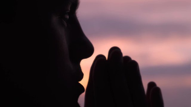 Close up of a man praying at sunset
