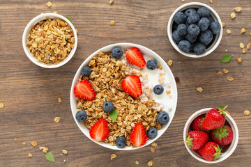 Breakfast smoothie bowl. Healthy smoothie bowl with granola, yogurt, strawberry and fresh blueberries on wooden background. Top view.