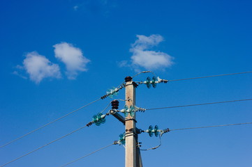 electric pole against blue sky with bird hiding 