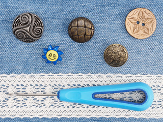 Beige lace, buttons, awl on a jeans background. Sewing still life
