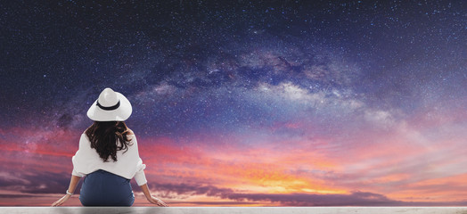 Young woman in white hat and cloth looking at beautiful starry sky with milky way at dawn 