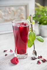 Red hibiscus tea in a transparent glass against the background of a vintage wall