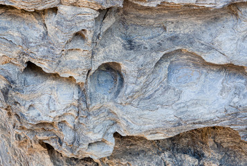 Rock carved by the forces of the waves of the sea, where you can see holes and layers of rock as if...
