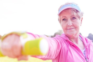 Determined senior woman exercising with dumbbell in park