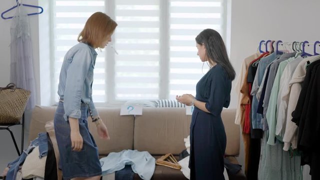 personal image-maker woman is working with female client in her home, they are viewing clothes and selecting