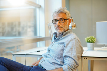 Portrait of smart casual businessman looking at camera in contemporary office