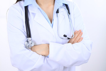 Stethoscope at female doctor breast at hospital office. Unknown physician's hands close-up. Medicine and health care concept