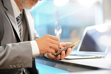 Close up of businessman's hands using stylus pen on cellphone