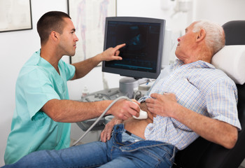 Man sonographer examining male patient - obrazy, fototapety, plakaty