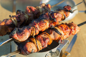 Food on the fire, picnic. Cooked grilled fragrant delicious hot grilled shashlik barbeque on coals on the grill of marinated pork, lamb and beef with onions on skewers on the table