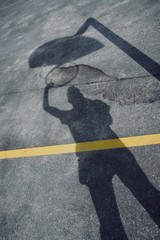 man playing basketball in the street, basket shadow silhouette