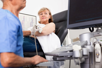 Obraz premium Dojrzały mężczyzna lekarz za pomocą USG bada pacjentkę w nowoczesnym szpitalu