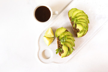 Healthy breakfast toasts with avocado, lime and coffee.