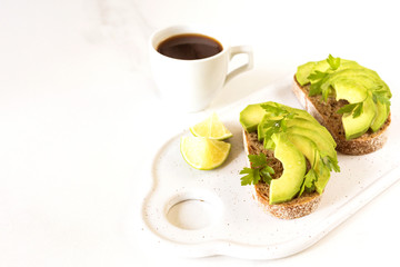 Healthy breakfast toasts with avocado, lime and coffee.