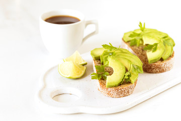 Healthy breakfast toasts with avocado, lime and coffee.
