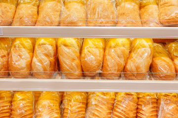 lots of fresh loaves of bread on shelves in store - 274875056