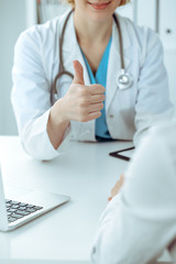 Close up of female doctor thumbs up. Happy cheerful smiling brunette physician ready to examine patient. Medicine, healthcare and help concept