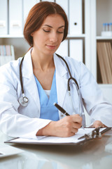 Doctor woman at work. Physician filling up medical history records form at the desk. Medicine, healthcare concept