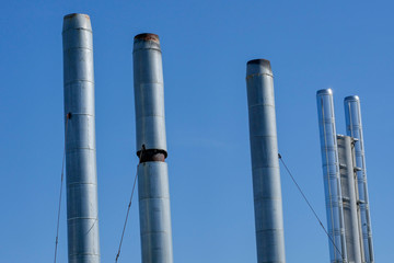 Pipes of gas boiler rooms on the background of blue summer sky. The smoke from the pipes does not go