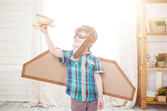 Child pretend to be pilot. Kid having fun at home. Summer vacation and travel concept. Little boy sits on a suitcase playing with model airplane. Fantasy travel concept. Children playing at home.