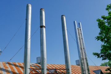 Pipes of gas boiler rooms on the background of blue summer sky. The smoke from the pipes does not go