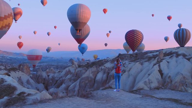 Female traveler with backpack looking to the air baloons. sporty girl and a lot of hot air balloons. The feeling of complete freedom, achievement, achievement, happiness