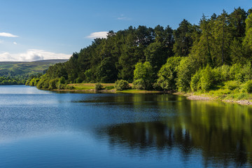 Fototapeta na wymiar Picturesque blue lake bordered by forests and green hills. Summer landscape at the Bohernabreena water supply Upper Reservoir in Glenasmole Valley, Dublin, Ireland. 