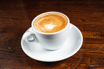 cup of cappuccino on the wooden background