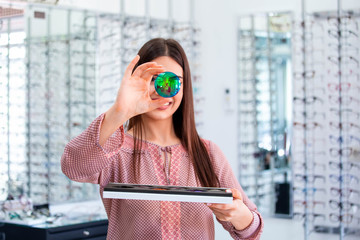 Attractive young female doctor in ophthalmology clinic showing different polarized lens