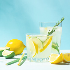 A refreshing lemon lime drink with ice cubes in glass goblets against a blue background. Summer...