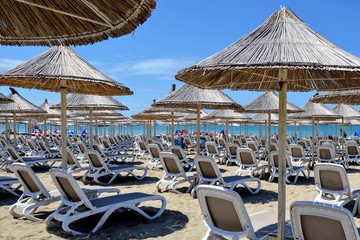 Umbrellas and chaise lounges on the sandy beach. Beach chairs, beds and umbrellas on a tropical...
