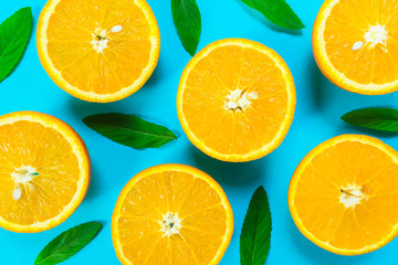  Colorful picture of fresh orange slices and mint leaves on a bright blue background. Top view