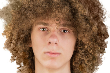portrait of a young curly European man with long curly hair and a defiant gaze looks into the frame...