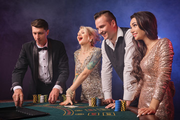 Group of a stylish rich friends are playing poker at casino.