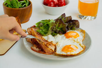 Hearty breakfast. Fried eggs, bacon, lettuce, cherry tomatoes and toast. Closeup