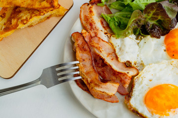 Hearty breakfast. Fried eggs, bacon, lettuce, cherry tomatoes and toast. Closeup